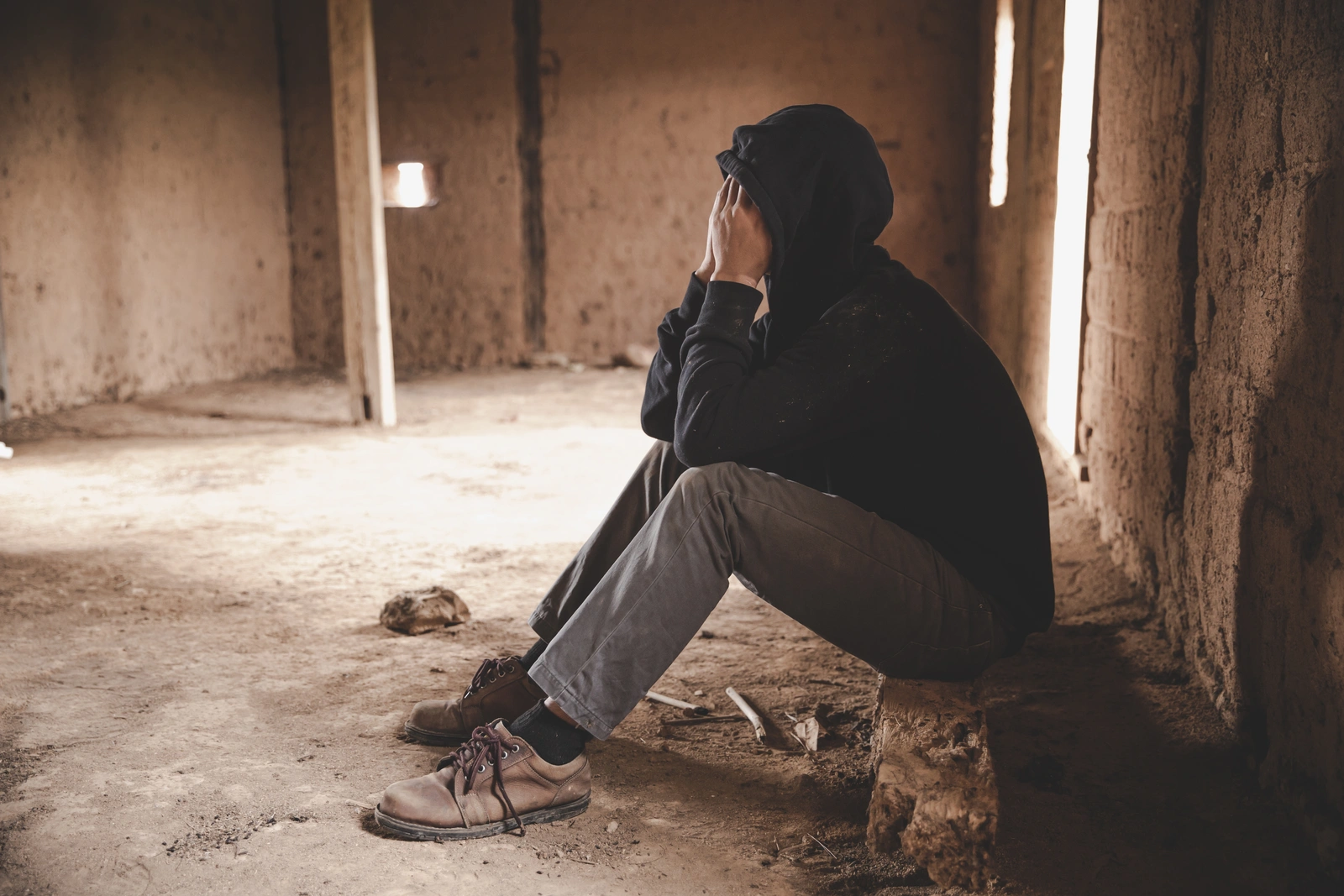a man sitting in a worn down building struggling with addiction